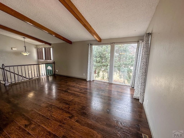 spare room featuring a textured ceiling, beamed ceiling, wood-type flooring, and baseboards