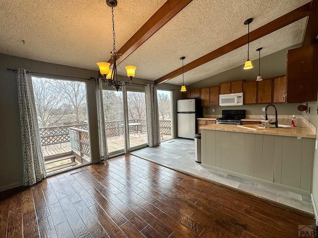 kitchen with appliances with stainless steel finishes, a sink, hardwood / wood-style floors, and brown cabinets