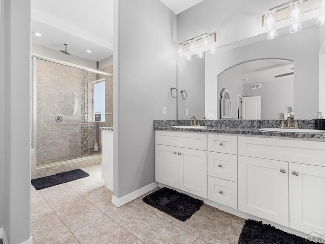 bathroom with a sink, baseboards, double vanity, and a stall shower