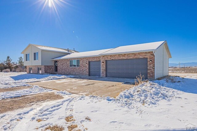 view of front facade with an attached garage, concrete driveway, and brick siding