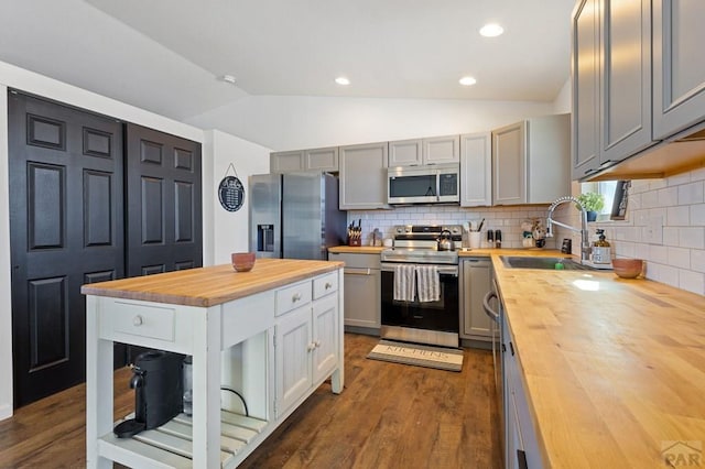 kitchen featuring stainless steel appliances, butcher block counters, a sink, and gray cabinets