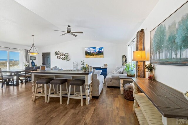 living area featuring lofted ceiling, a ceiling fan, and dark wood-style flooring