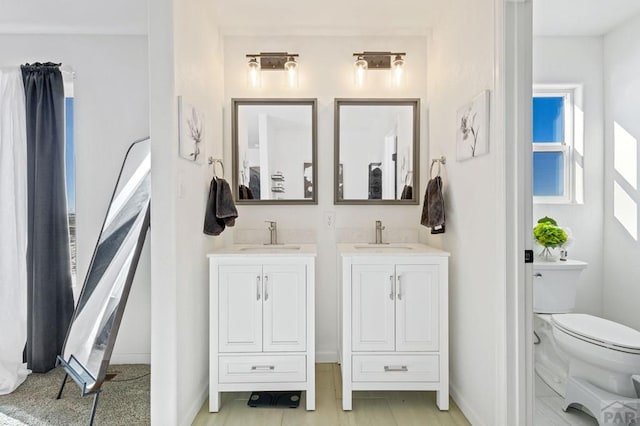 bathroom with toilet, vanity, and baseboards