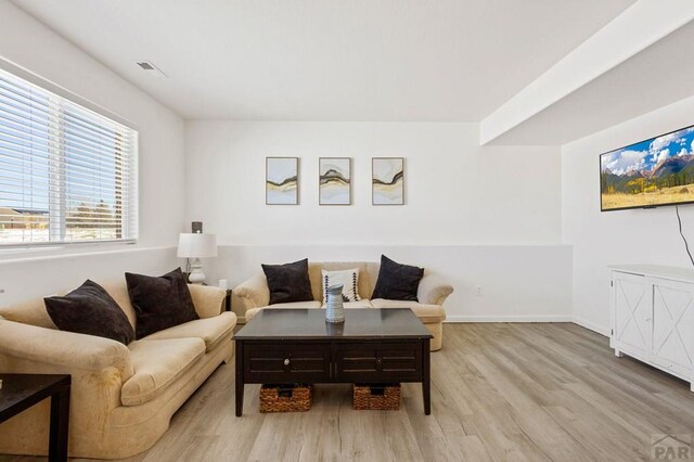 living room with visible vents, light wood-style flooring, and baseboards