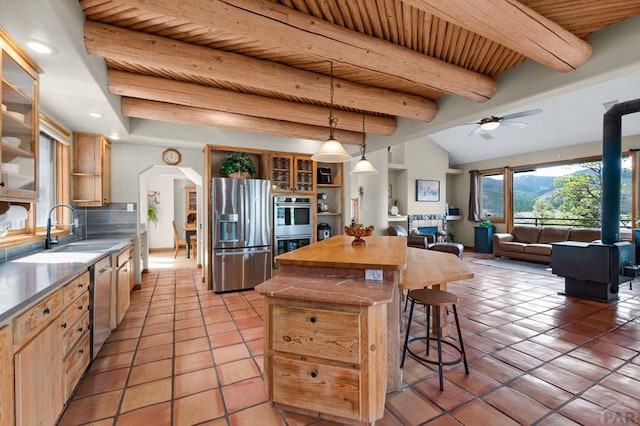 kitchen featuring a kitchen bar, light tile patterned floors, stainless steel appliances, wood ceiling, and a sink