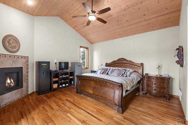 bedroom featuring a ceiling fan, wood ceiling, a tile fireplace, and light wood-type flooring