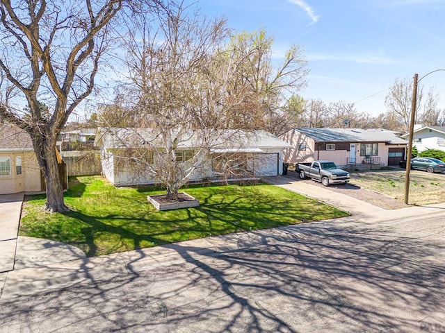 view of front of home with a garage, fence, driveway, a residential view, and a front yard