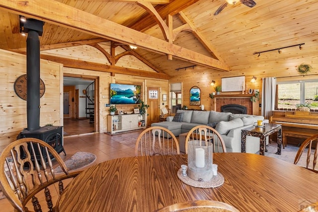1800 Oak Grove Cir, Westcliffe, CO 81252 - dining room with wood walls, wooden ceiling with exposed beams, a wood stove, tile patterned floors, and a brick fireplace