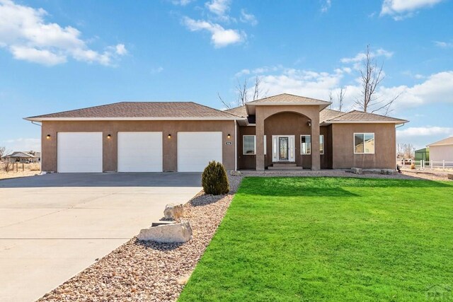 ranch-style house featuring concrete driveway, a front lawn, an attached garage, and stucco siding