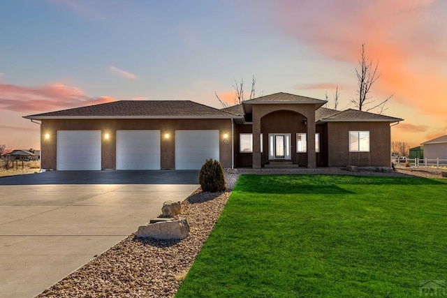 view of front of house featuring a garage, a lawn, concrete driveway, and stucco siding