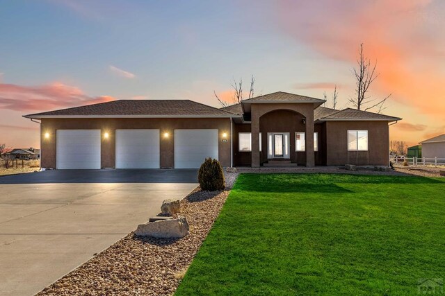 view of front of house featuring a garage, a lawn, concrete driveway, and stucco siding