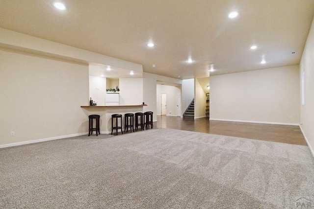 interior space featuring a dry bar, recessed lighting, dark carpet, baseboards, and stairs