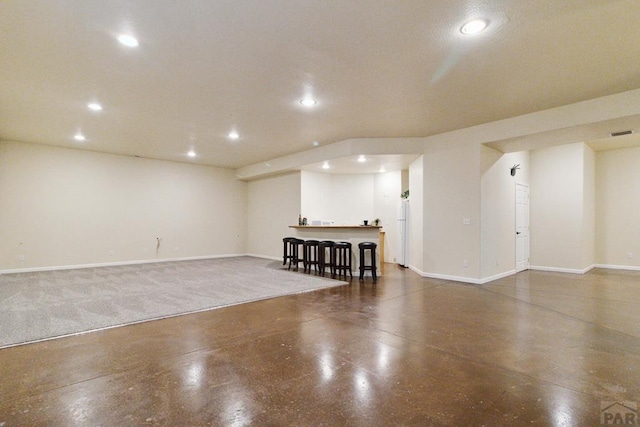 finished basement featuring baseboards, bar area, visible vents, and recessed lighting