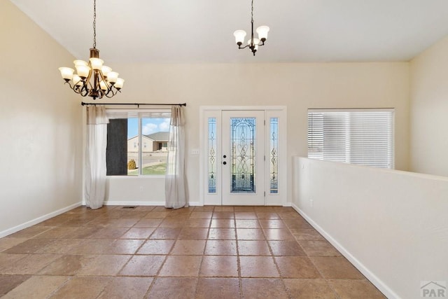 entrance foyer with baseboards, vaulted ceiling, stone tile flooring, and a notable chandelier