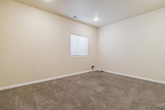 carpeted spare room featuring visible vents and baseboards