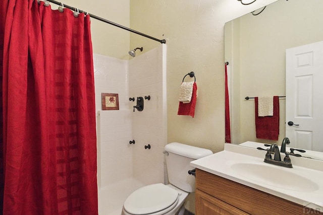 bathroom featuring toilet, a tile shower, and vanity