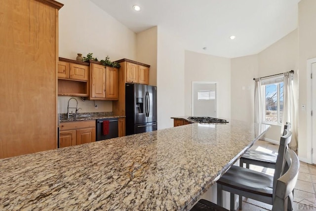 kitchen featuring light stone counters, a breakfast bar, black appliances, open shelves, and a sink