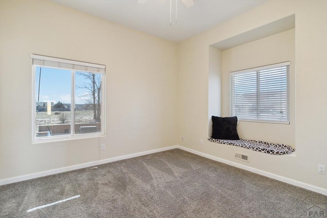 carpeted empty room with a ceiling fan, visible vents, and baseboards