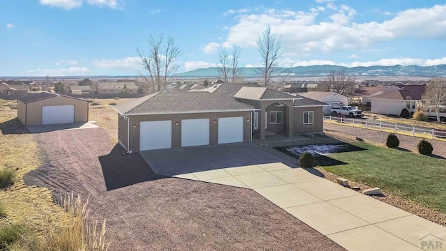 single story home with concrete driveway, a residential view, a mountain view, and a front yard