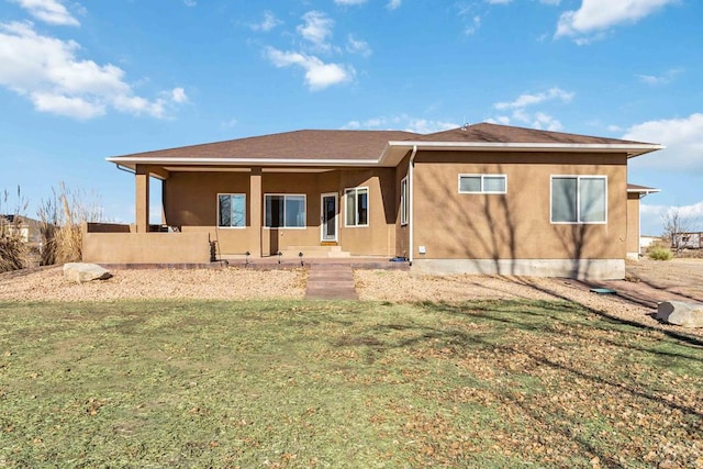 rear view of property with a lawn and stucco siding