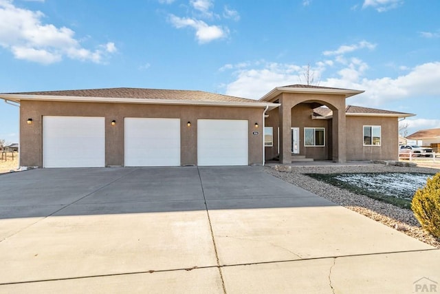 view of front facade featuring driveway, an attached garage, and stucco siding