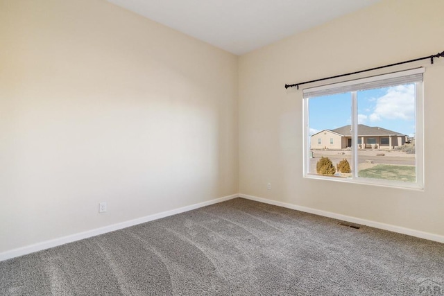 spare room with carpet floors, visible vents, and baseboards