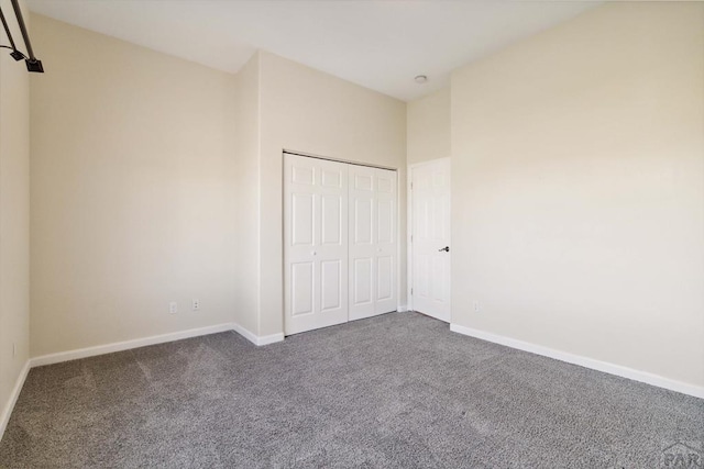 unfurnished bedroom featuring a closet, dark carpet, and baseboards