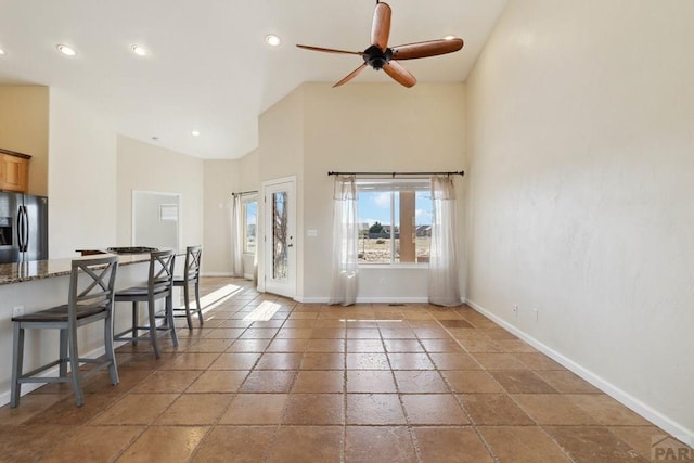 interior space featuring baseboards, ceiling fan, stone tile flooring, high vaulted ceiling, and recessed lighting