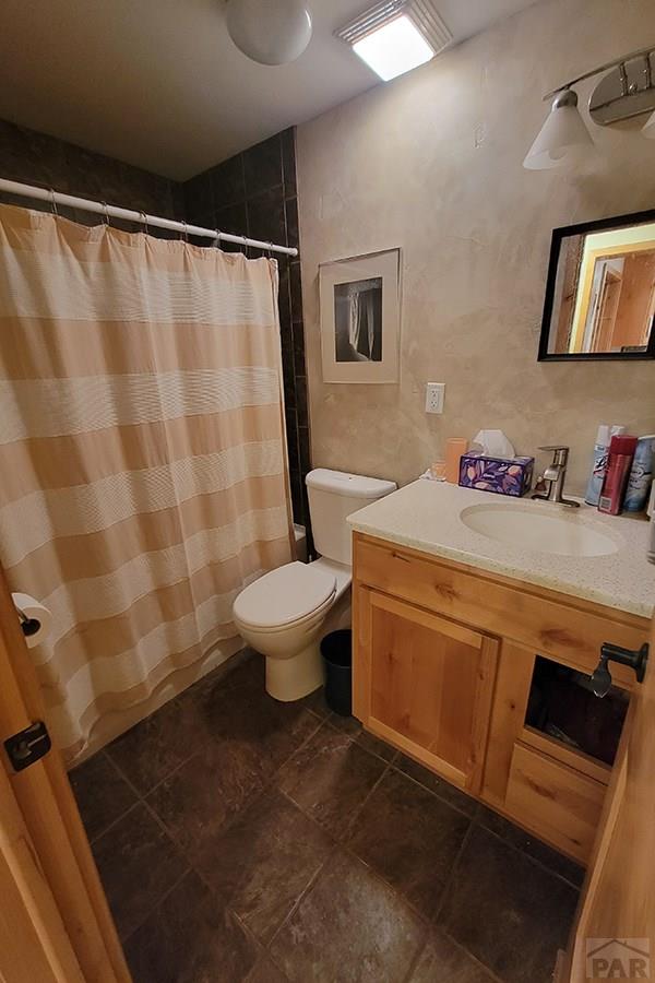 bathroom with toilet, curtained shower, and vanity