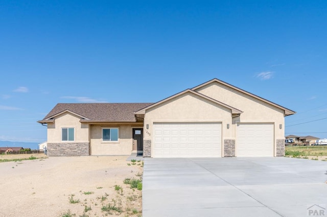 single story home with stone siding, an attached garage, and stucco siding