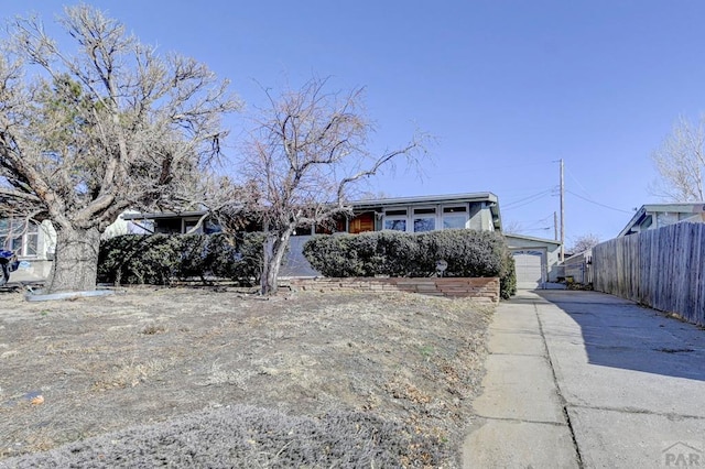 view of front of home featuring a garage, concrete driveway, and fence