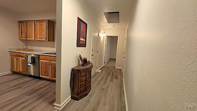 corridor with a textured wall, wood finished floors, and baseboards