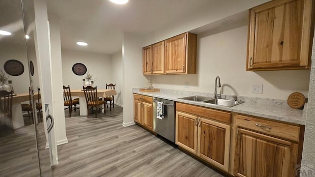 kitchen featuring light wood finished floors, baseboards, brown cabinetry, stainless steel dishwasher, and a sink