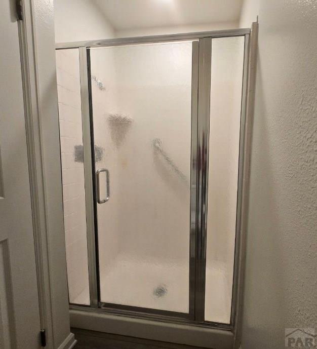 full bathroom with a textured wall and a shower stall