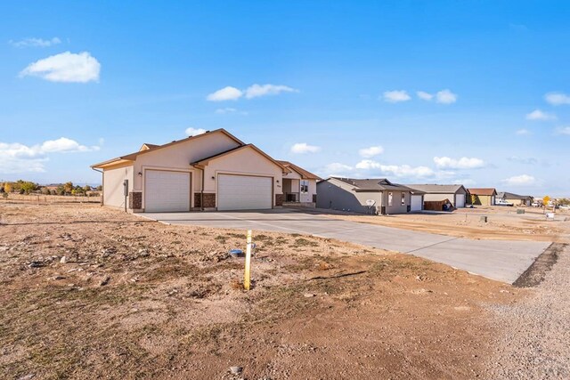 ranch-style house with an attached garage, a residential view, concrete driveway, and stucco siding