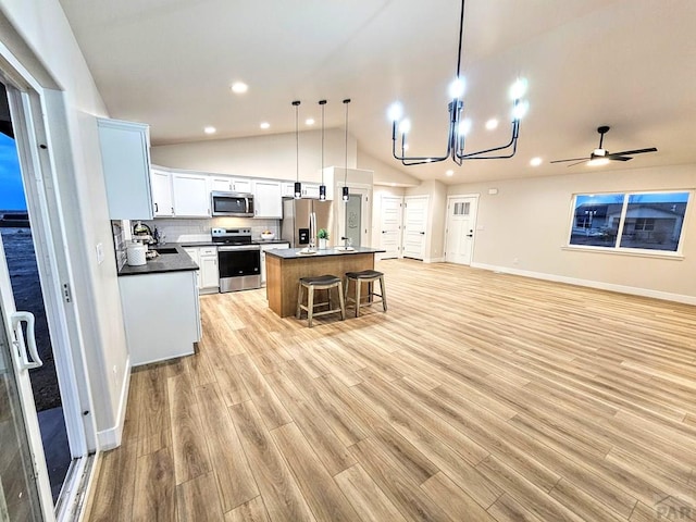 kitchen with a sink, a kitchen island, open floor plan, stainless steel appliances, and lofted ceiling