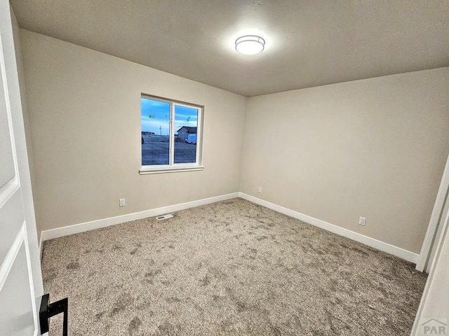 empty room with visible vents, baseboards, and carpet floors