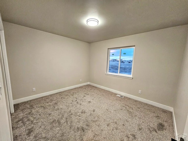 carpeted spare room with visible vents and baseboards