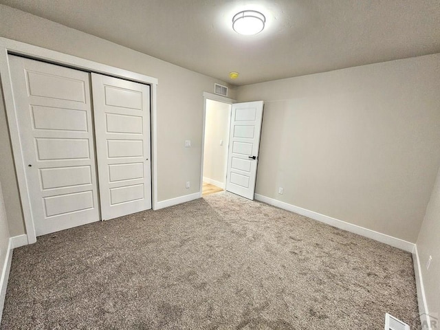 unfurnished bedroom featuring a closet, visible vents, baseboards, and carpet floors