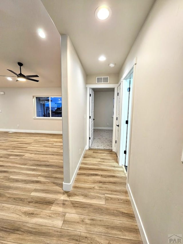 corridor featuring light wood finished floors, visible vents, recessed lighting, and baseboards