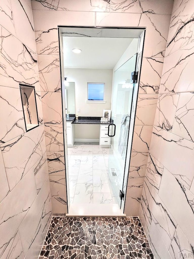 bathroom with vanity, stone wall, and a marble finish shower