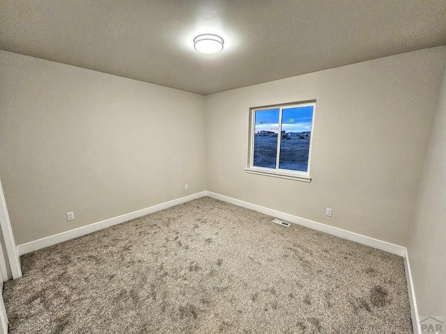 carpeted empty room featuring visible vents and baseboards