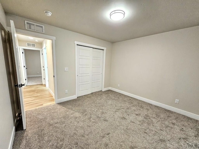 unfurnished bedroom with visible vents, carpet floors, baseboards, and a closet