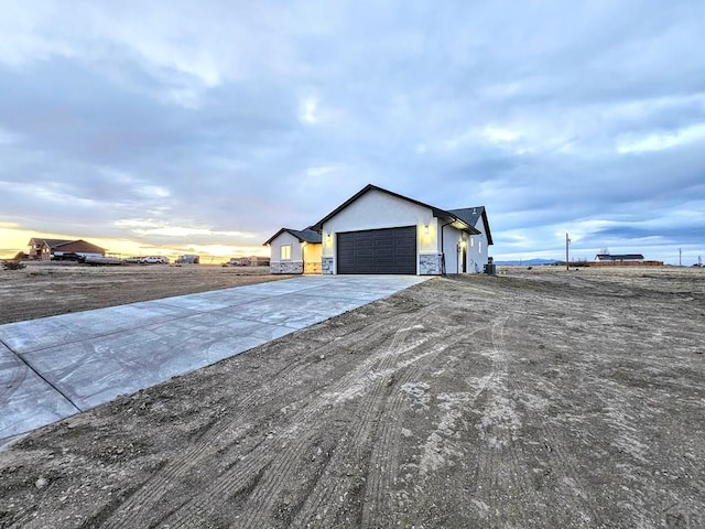 view of home's exterior featuring stucco siding, stone siding, concrete driveway, and an attached garage