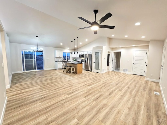 kitchen featuring visible vents, stainless steel appliances, white cabinetry, open floor plan, and a center island