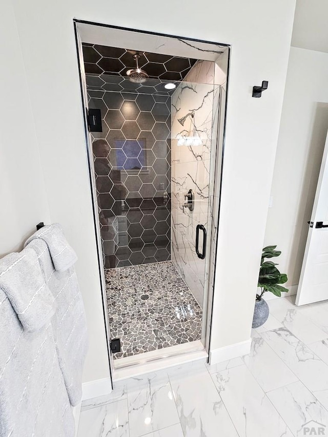 full bath featuring baseboards, marble finish floor, and a stall shower