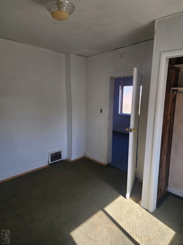 empty room with dark colored carpet, visible vents, and baseboards