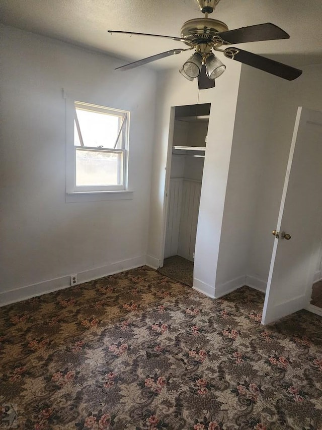 unfurnished bedroom with a closet, dark carpet, a ceiling fan, and baseboards