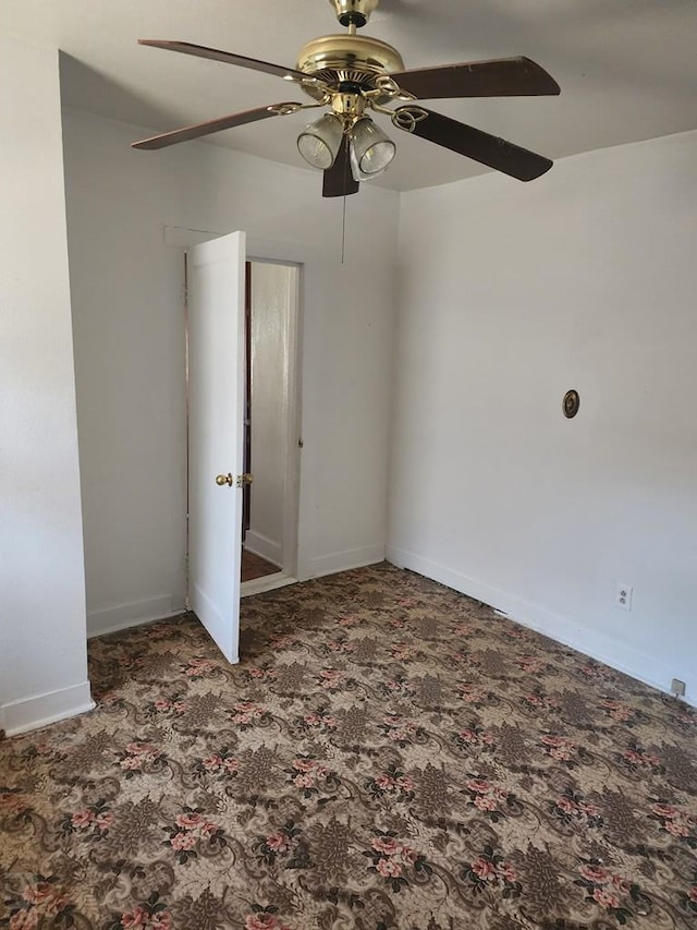 empty room featuring baseboards, dark colored carpet, and a ceiling fan