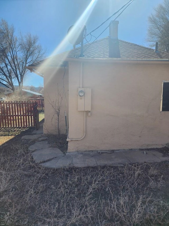 view of side of property featuring fence and stucco siding